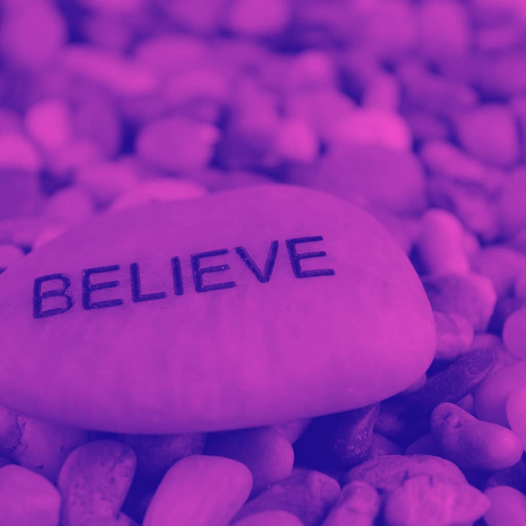 Image of a rock with the word believe on it.