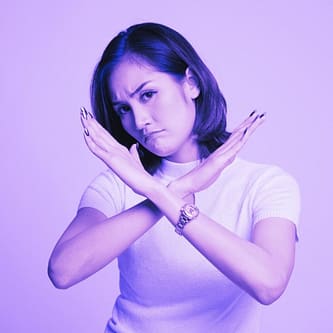 Woman with arms forming an X in front of her to non-verbally represent saying no.