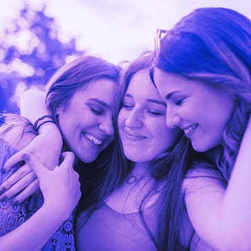 Three friends sharing an embrace.