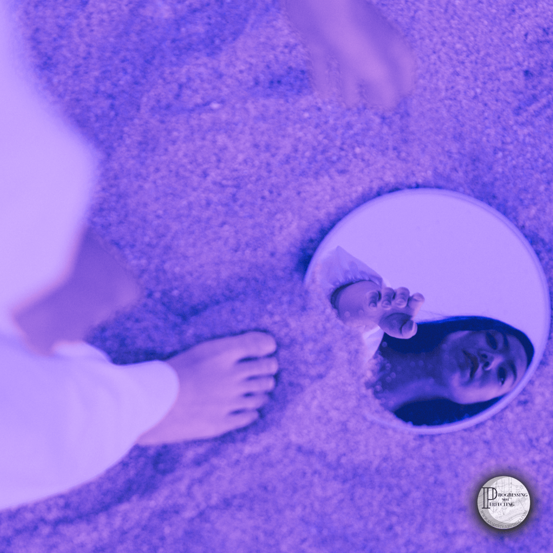 a person looking into a mirror in the sand