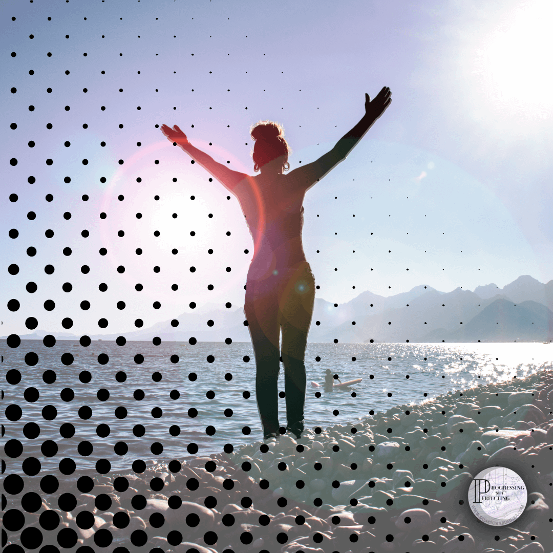a woman standing on a beach with her arms raised